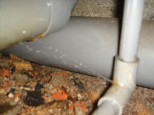 床下の塩ビ管（給水管）が劣化していて穴が開き水が噴き出している写真